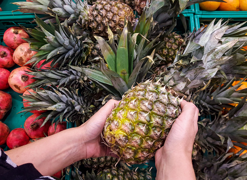 Female hand holding a pineapple in supermarket