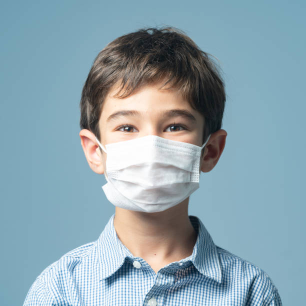 istock Mugshot Of Elementary Schoolboy Smiling behind Protective Face Mask 1343372737