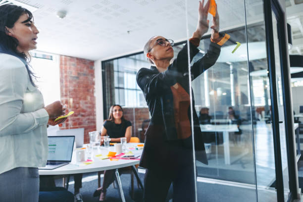 istock Creative businesswomen sticking adhesive notes to a glass wall 1343397232