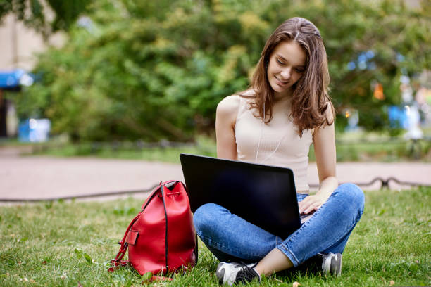 istock Young woman sits in park with laptop during online learning. 1343398509