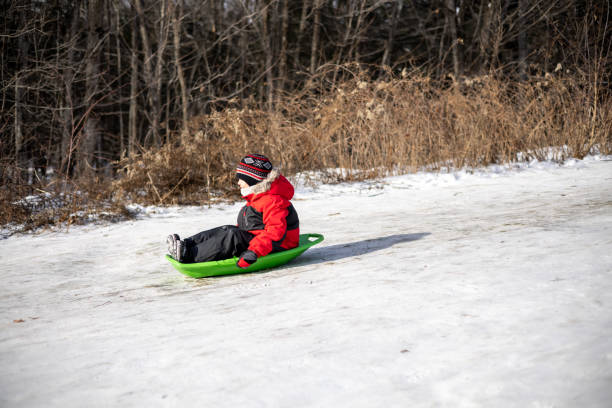 kleiner junge schlitten im winter im schnee im freien - little boys sled clothing slide stock-fotos und bilder