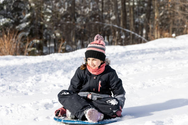 маленькая девочка катание на санках на снегу на открытом воздухе зимой - playground snow winter little girls стоковые фото и изображения