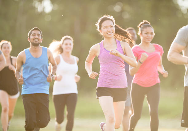 young sporty woman with blond hair jogging with a smile in rural surrounding sun flares create backlight and golden hour effect enjoying the evening sun