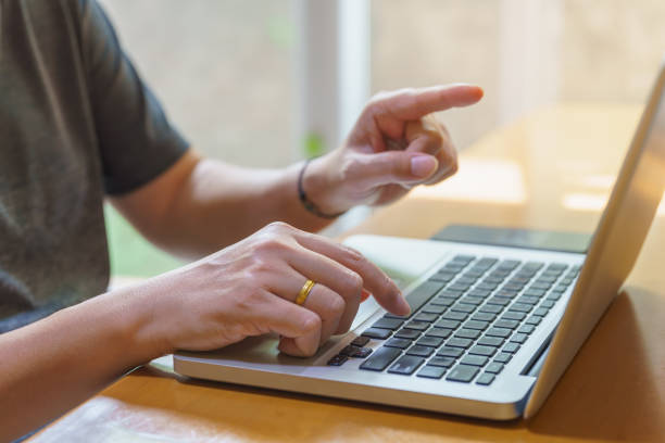 istock Business and Work From Home and Technology Concept. Asian man using and typing computer laptop and finger pointing to screen on wooden table.. 1343401435