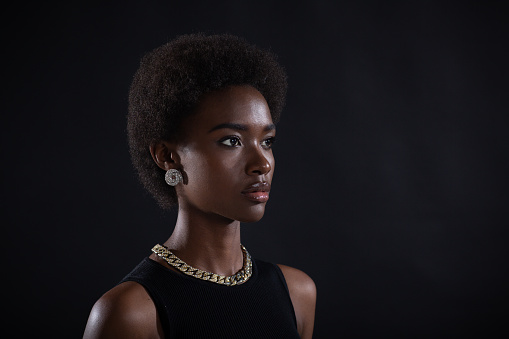 Close up half turn portrait of african american woman with afro hairstyle on black studio background.