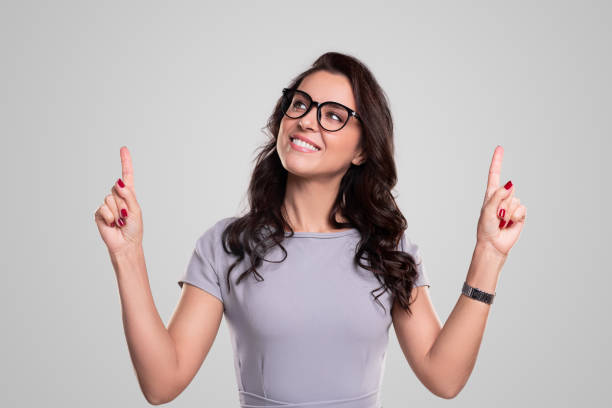 istock Cheerful woman in glasses pointing up 1343404104