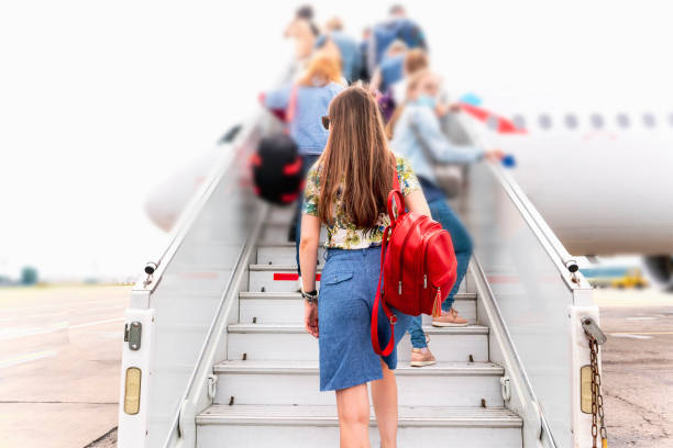 young woman walking on the airplane jet ladder stairs moving to the vacation stock photo