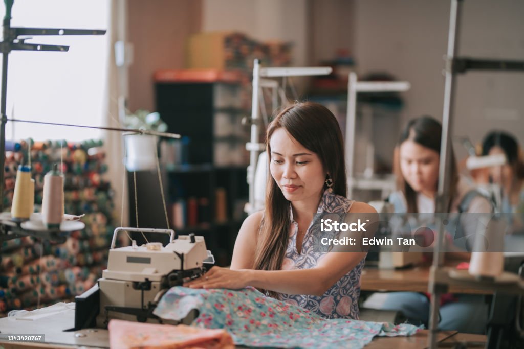asian chinese female blue collar worker working in sewing studio in a row Sewing Stock Photo