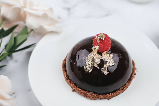 Chocolate mousse Cake with berries with rose flower on marble table. Delicious homemade cake.