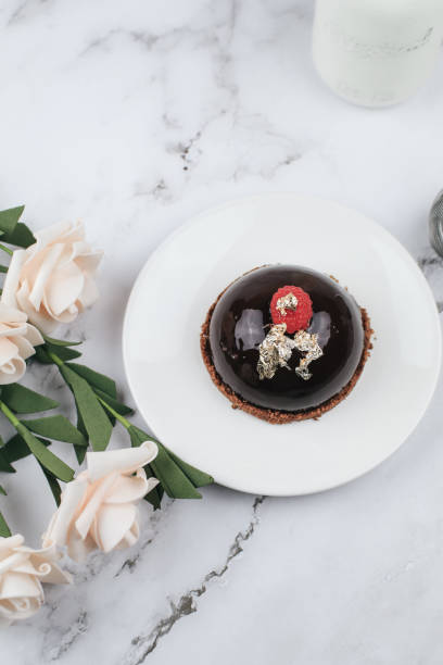 Chocolate mousse Cake with berries with rose flower on marble table. Delicious homemade cake.