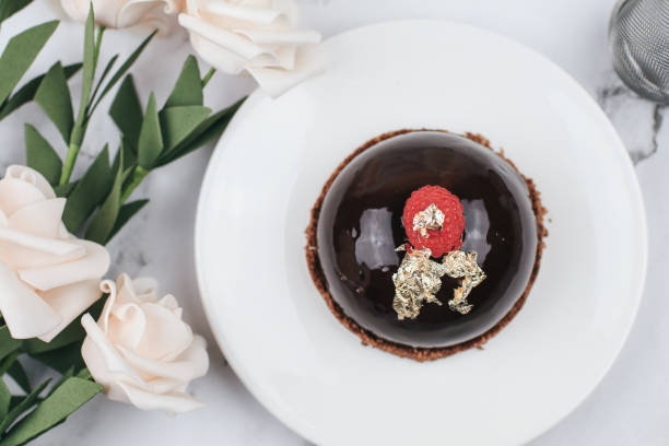 Chocolate mousse Cake with berries with rose flower on marble table. Delicious homemade cake.