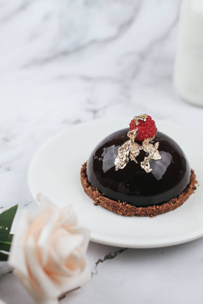 Chocolate mousse Cake with berries with rose flower on marble table. Delicious homemade cake.
