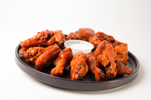 Hot and spicy buffalo chicken wings close up on a white background with blue cheese dip