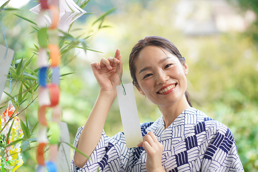 A woman who attaches a strip of paper to Tanabata bamboo