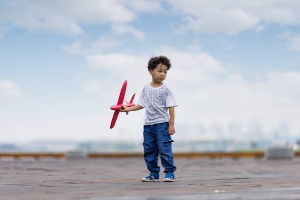 A little boy playing with a model plane in the park