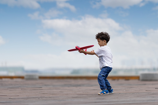 A little boy playing with a model plane in the park