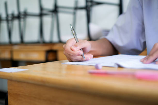 istock Hand female Asian students taking exam test and concentration reading document exercise at classroom in high school. Teenager notes for SAT PISA measurement educational, back to school for evaluation 1343453110