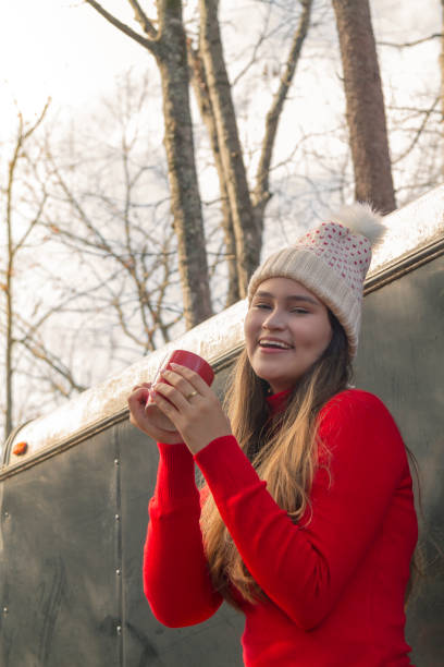 istock Young latin woman portrait while she's drinking a cup of coffee / chocolate, while taking a rest in the middle of pine crest forest in a cold Thanksgiving / Christmas autumn morning / afternoon. 1343453506