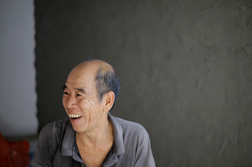 An Asian senior man is doing renovation at home joyfully.