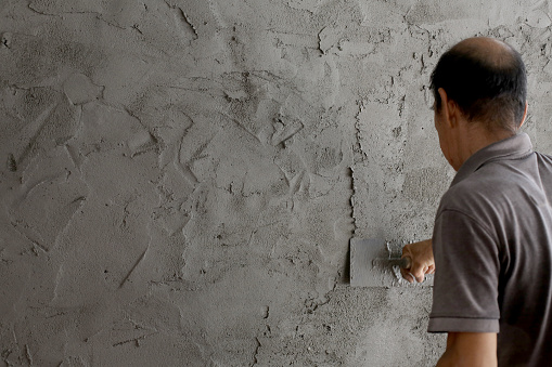 An Asian senior man is doing renovation at home.