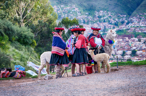 Cusco, Peru - 23 Feb 2020: Peruvian Inca woman smiling with traditional andean clothing stand together with Alpaca in Cusco, Peru