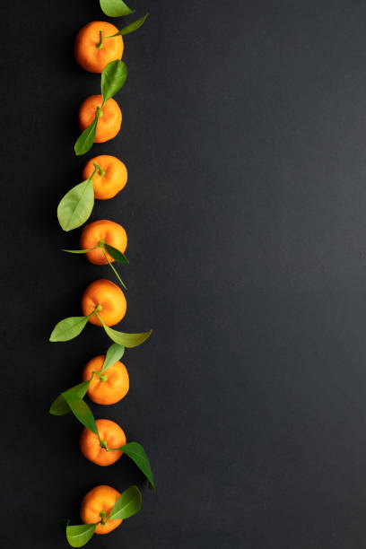 istock Clementines with leaves on a black background. Top view with copy space. 1343456953