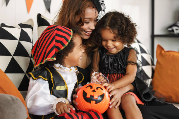 счастливая африканская семья в костюмах празднует праздник хэллоуин вместе дома - women halloween thanksgiving african ethnicity стоковые фото и изображения