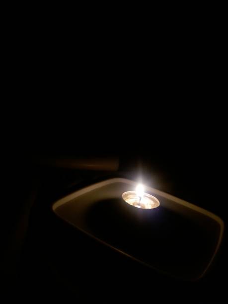 istock A lit candle lit up the dark room. 1343460482