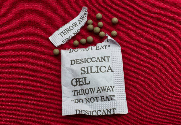 istock Desiccant silica gel on red background. Synthetic substance absorbing moisture 1343464724