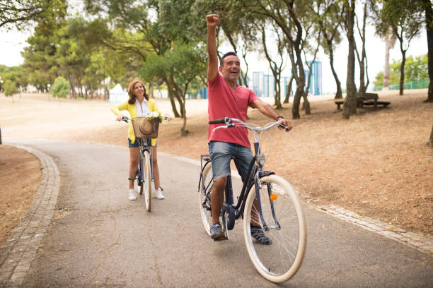 istock Excited mature couple riding bicycles in park 1343465175