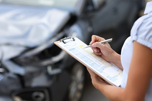Insurance agent inspects damaged vehicle. Car insurance concept