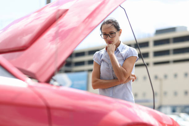 Pensive woman looks at car engine closeup Pensive woman looks at car engine. Car breakdown on the road concept engine failure stock pictures, royalty-free photos & images