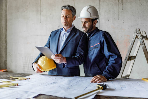 istock Mid adult architect and manual worker using touchpad at construction site. 1343471335