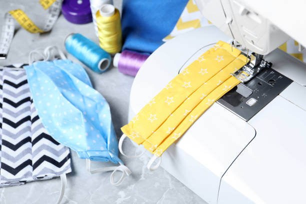 istock Sewing machine, homemade protective masks and craft accessories on grey marble table 1343477727