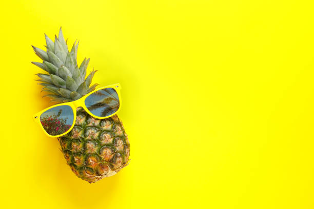 istock Pineapple and sunglasses with reflection of palm trees on yellow background, top view. Space for text 1343478599