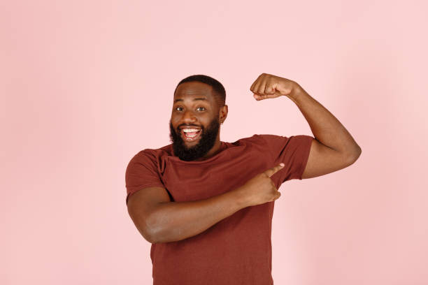 istock Handsome African-American man points to muscles on pink 1343478668