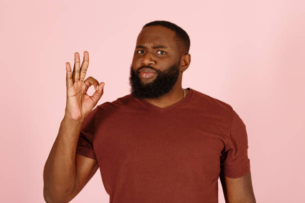 Handsome black guy model shows OK gesture standing on pink stock photo