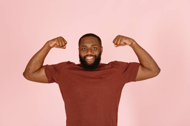 istock Handsome African-American man demonstrates muscles on pink 1343478710
