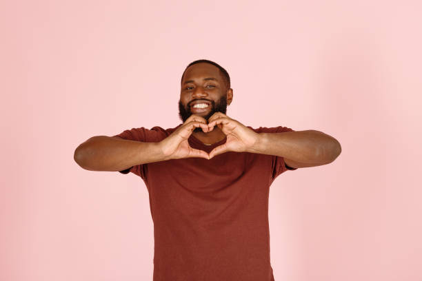 Smiling African-American man shows heart with palms stock photo