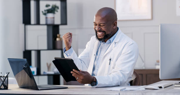 Shot of a male doctor excitedly cheering in his office while using a digital tablet stock photo