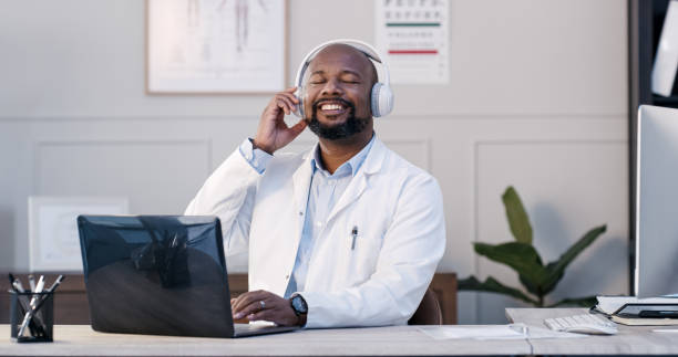 Shot of a male doctor listening to music using his headphones stock photo