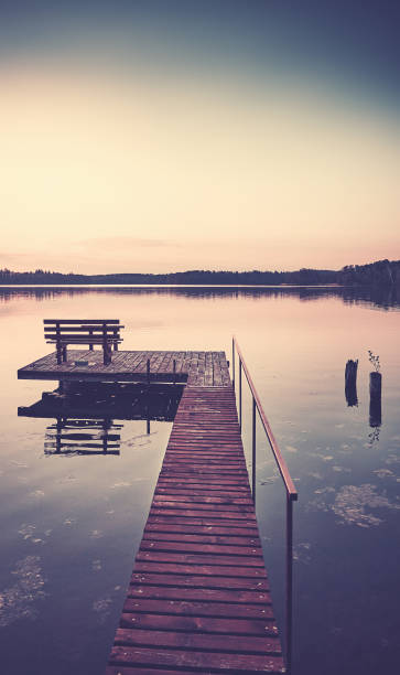istock Wooden lake pier with bench at sunset. 1343482100