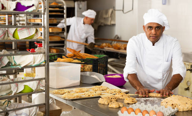 istock Male baker working with dough forming baguettes 1343482774