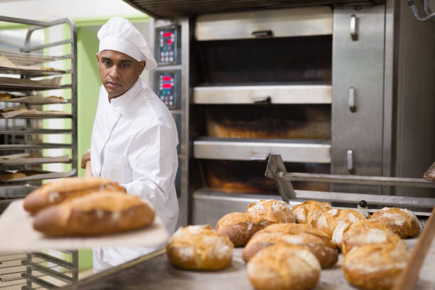 istock Man holding bread on peel in bakery 1343482785