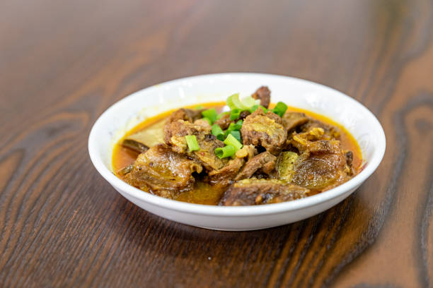 The beef dish is in the plate on the wooden table