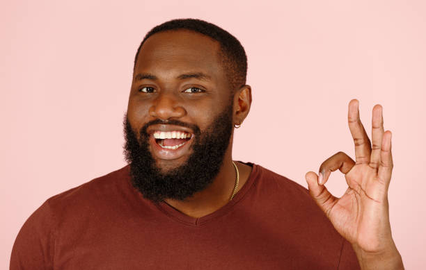 istock Joyful black guy model shows OK gesture standing on pink 1343486275