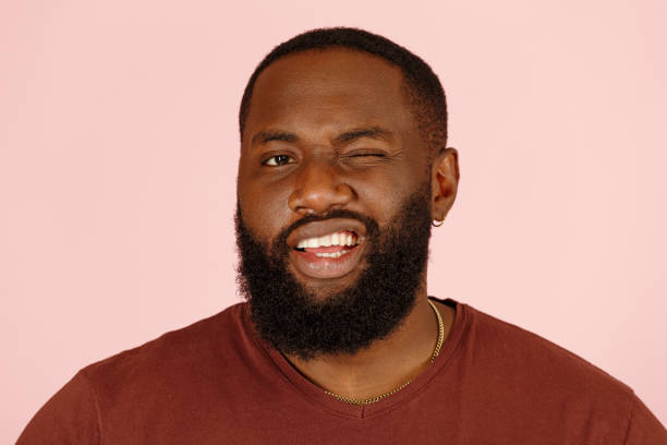 istock Attractive African-American man model winks standing on pink 1343486306