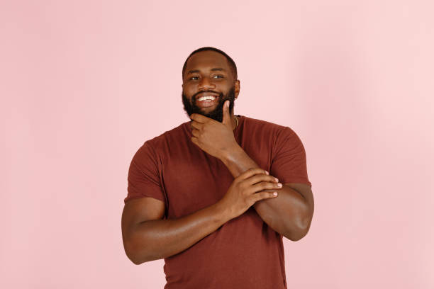 istock Thoughtful Afro-American person touches beard on pink 1343486348