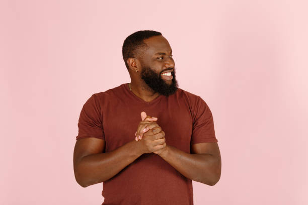 istock Smiling African-American man trickster rubs hands on light pink 1343486548