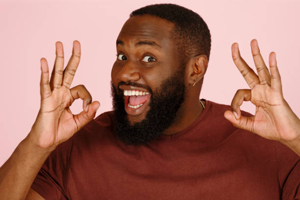 istock Joyful black guy model shows OK gesture standing on pink 1343486790